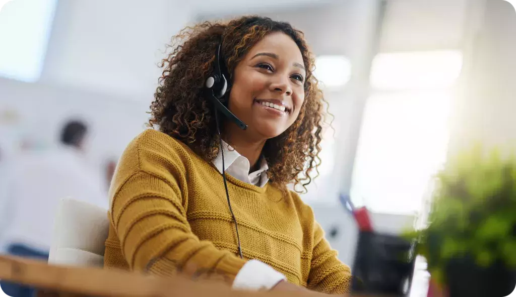 person wearing a headset smiling while looking at computer screen