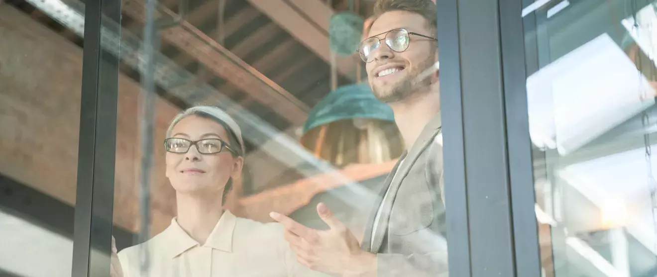 Woman and man casually looking out of an office window
